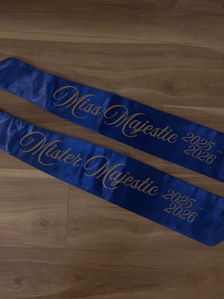 Two royal blue sashes with gold cursive text reading "Miss/Mr. Majestic 2025-2026".