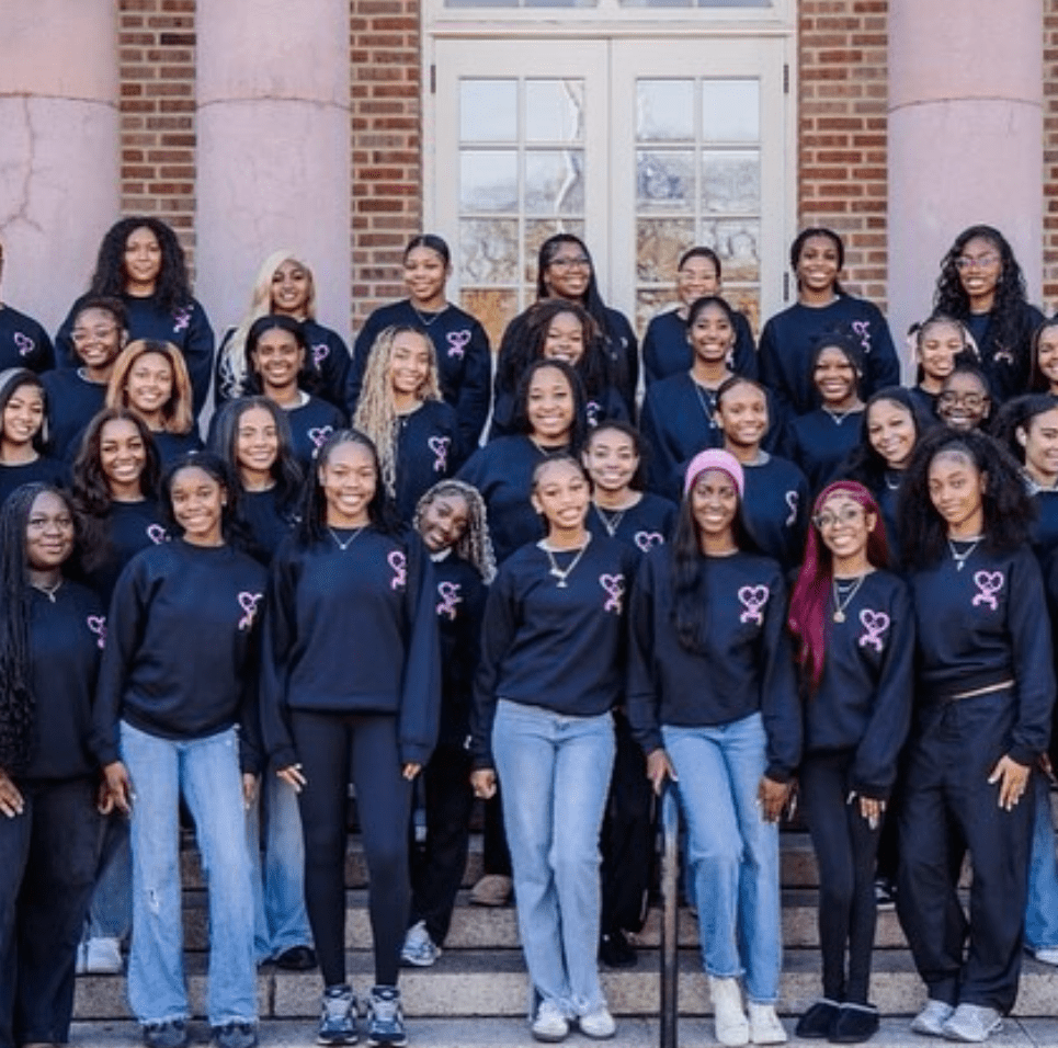 Hearts of Harmony members wearing matching black crewnecks pose together on campus steps for an official organization photo.