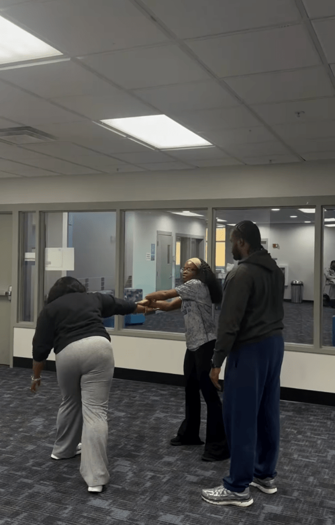 Participants practice a self-defense maneuver in a campus multipurpose room during the workshop hosted as part of Miracle Gross’s platform programming.